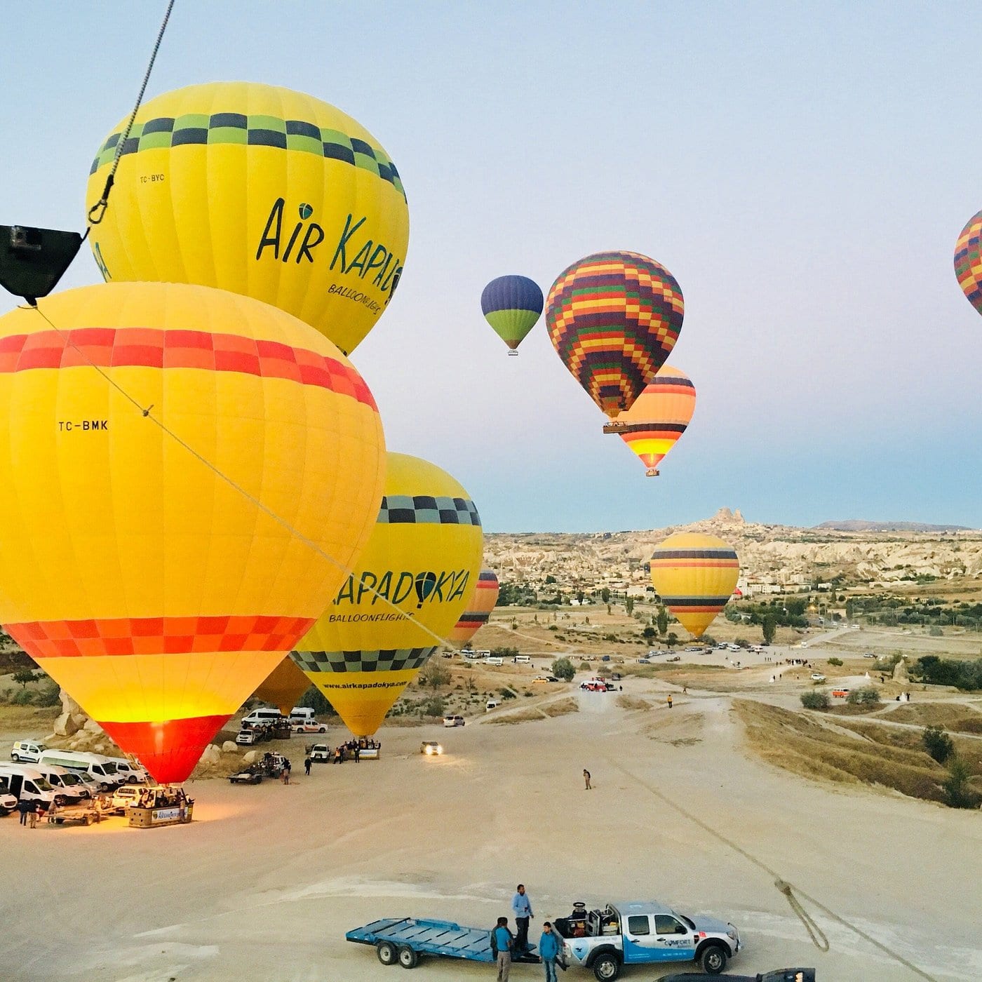 Decine di mongolfiere colorate che si gonfiano una accanto all’altra su un campo di decollo in Cappadocia alle prime luci