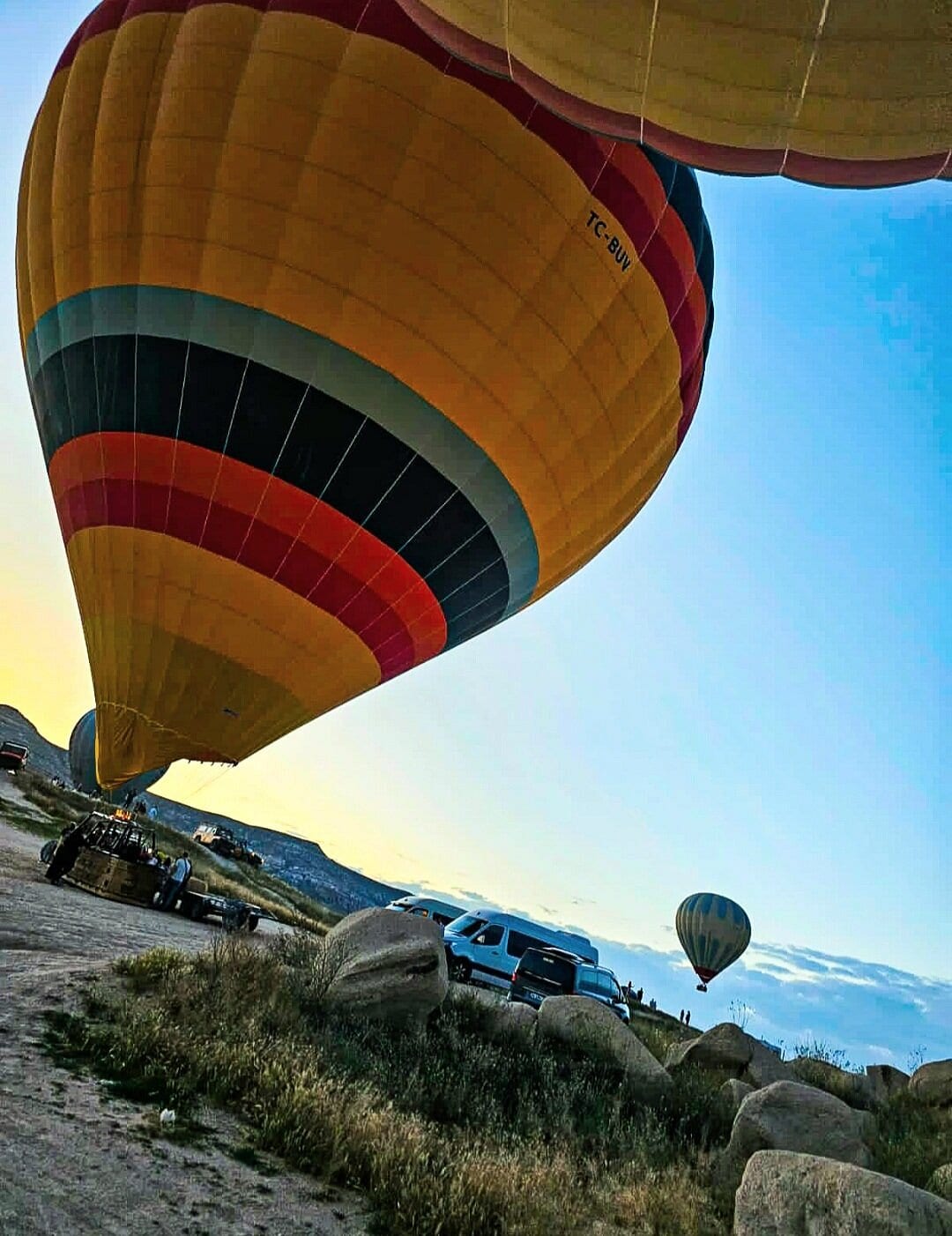 Una mongolfiera gialla e nera che si gonfia sul campo di decollo all’alba in Cappadocia, vista dal basso