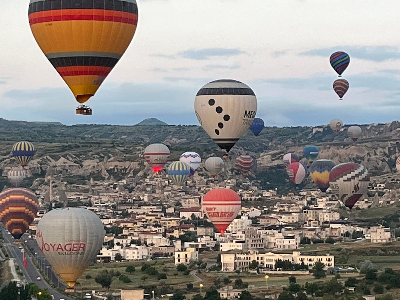 Decine di mongolfiere che scivolano basse sulle case di pietra di una cittadina della Cappadocia all’alba
