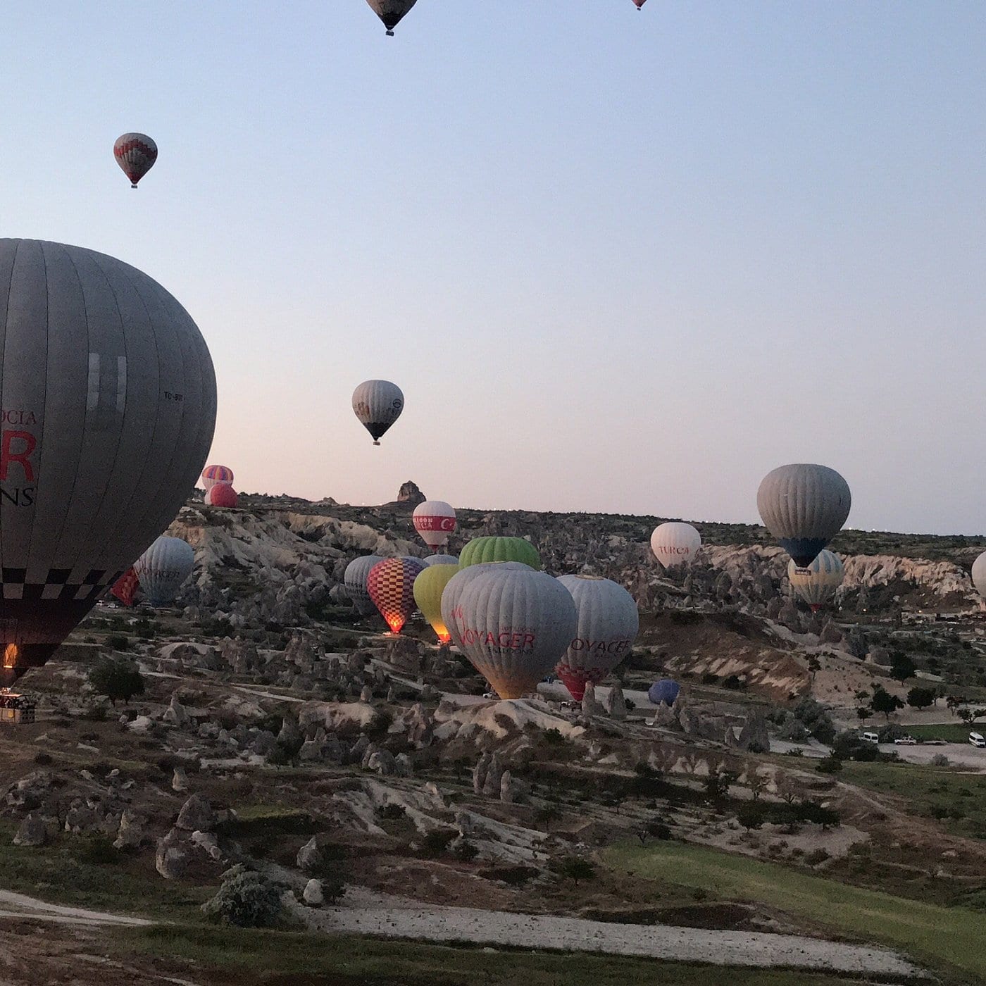 Mongolfiere sparse sulla valle della Cappadocia tra i camini delle fate nella luce morbida del crepuscolo