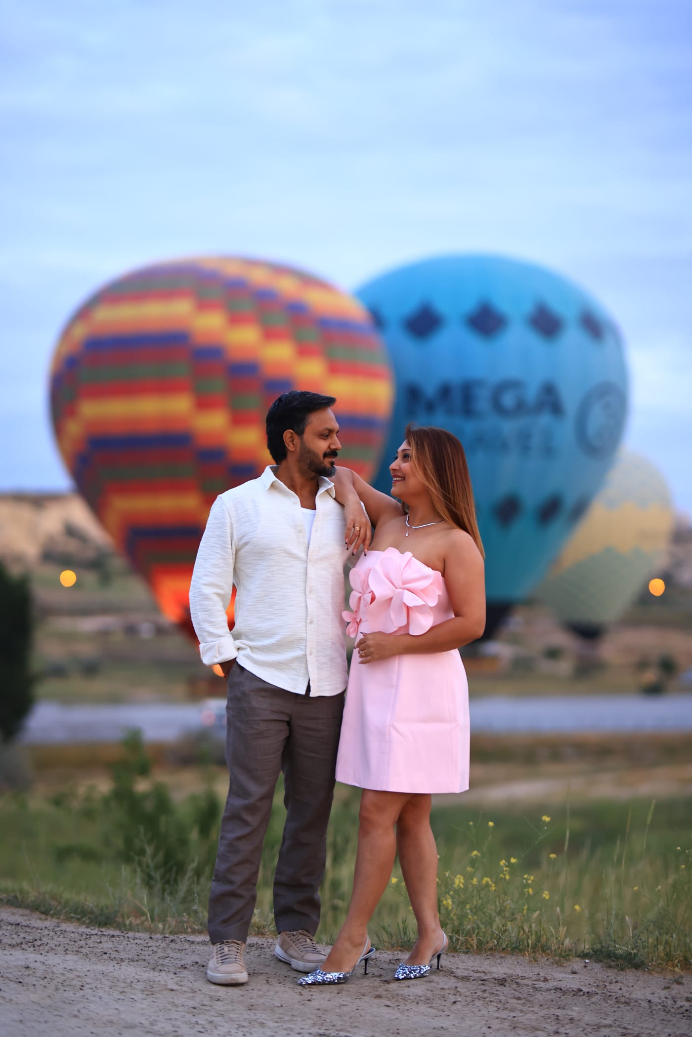 Una coppia in abito elegante che si abbraccia davanti a una grande mongolfiera colorata a terra in Cappadocia