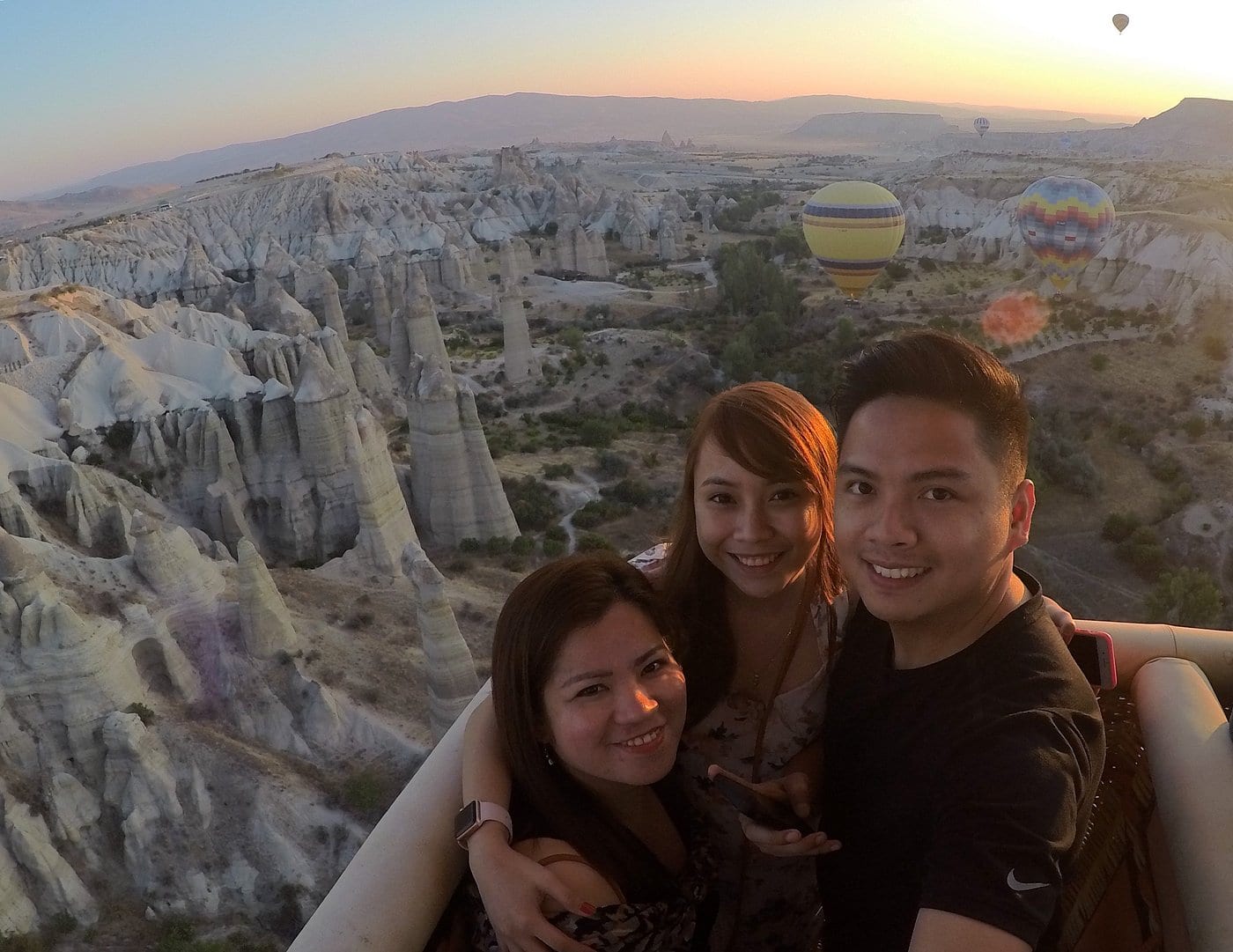 Tre amici che si fanno un selfie insieme nella cesta di una mongolfiera sulla Valle dell’Amore in Cappadocia all’alba