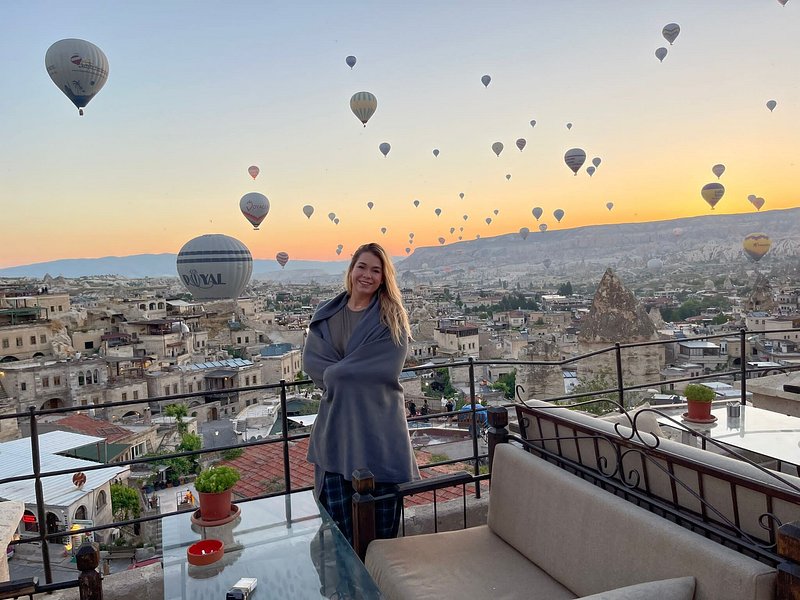 A guest watches hundreds of hot air balloons rise from a Cappadocia hotel terrace at sunrise