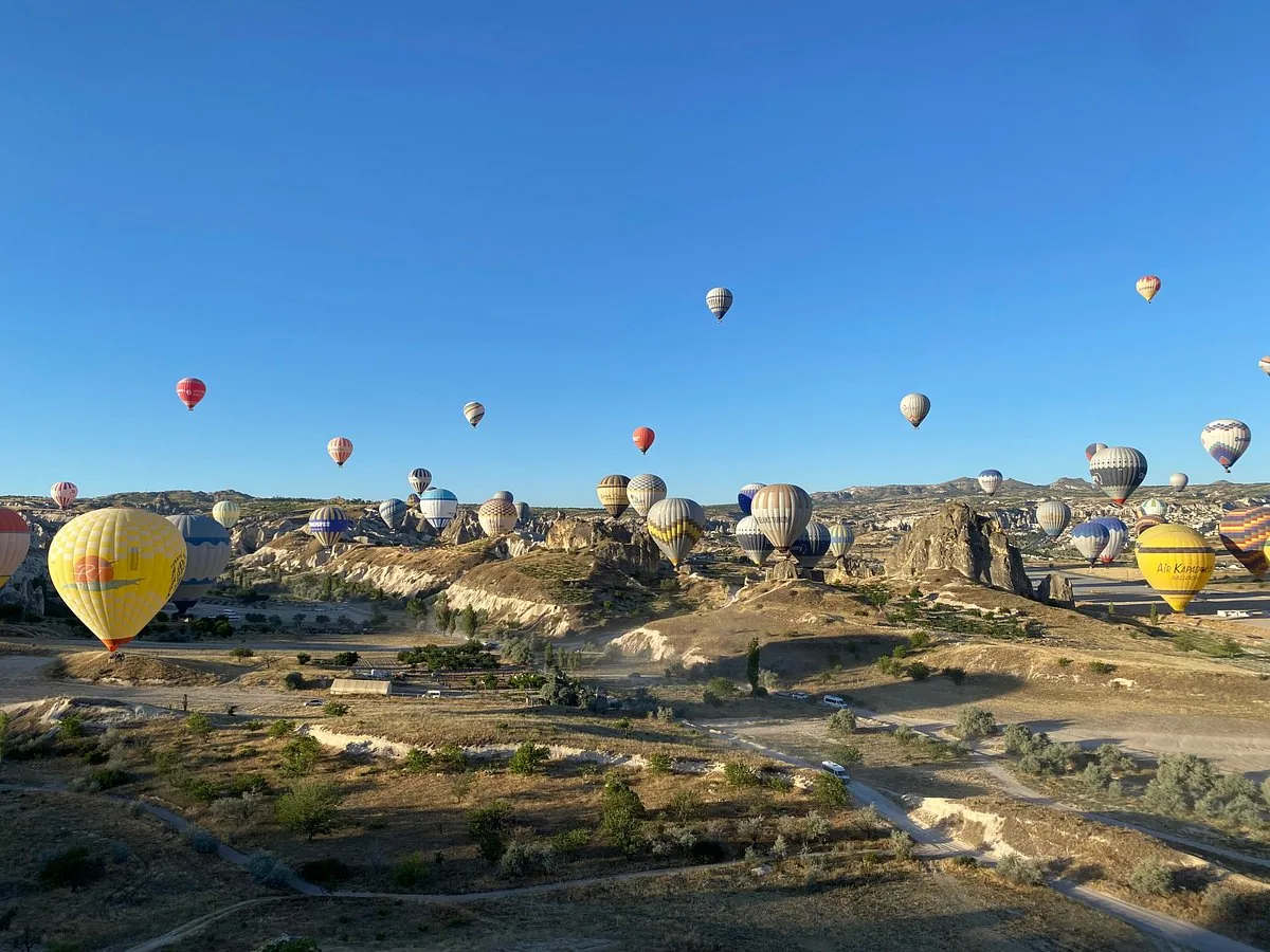 Dozens of hot air balloons rising over the fairy chimneys and launch fields of the Goreme valley