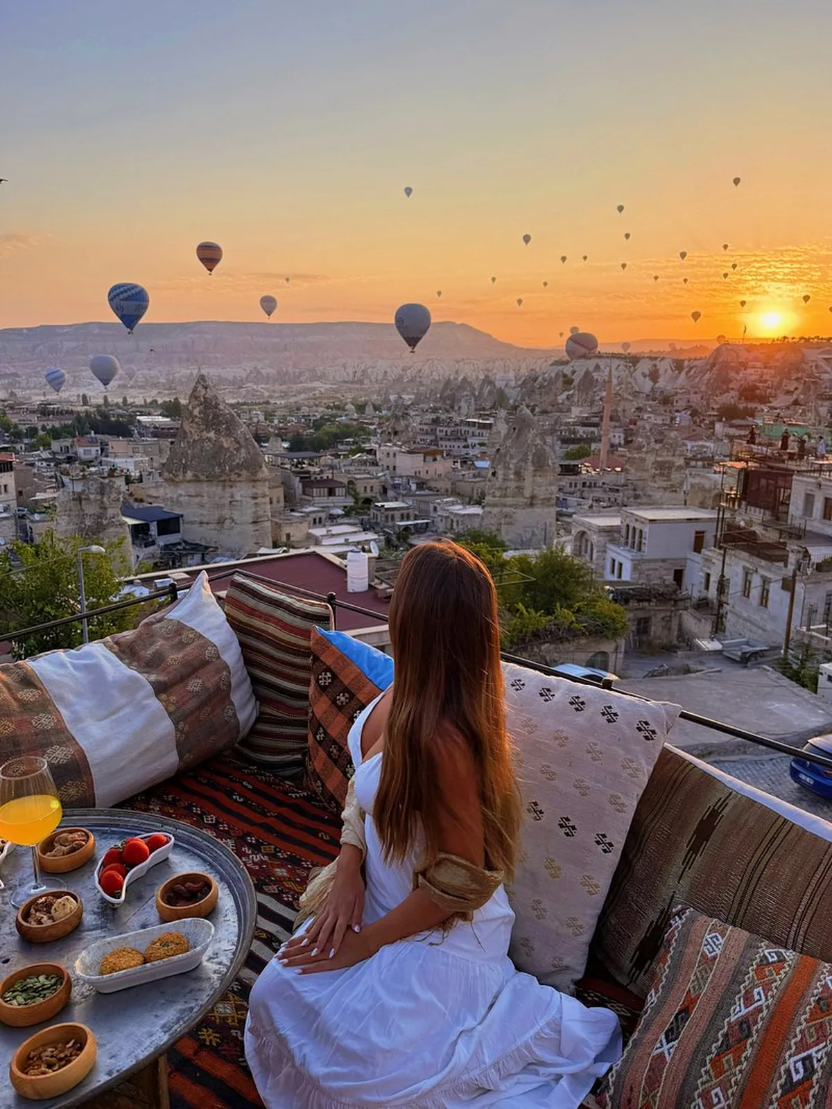 A rooftop terrace in Goreme with a Turkish breakfast and a view of balloons over the valley at sunrise