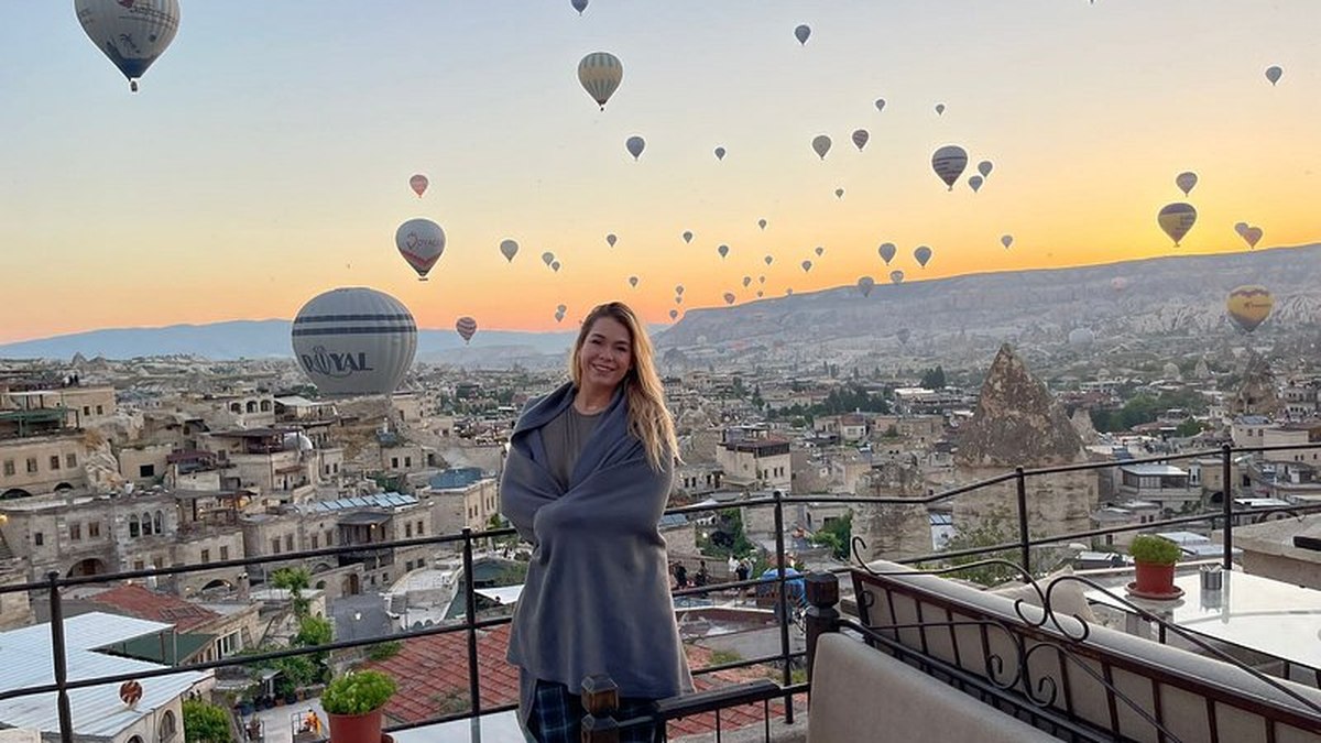 Un’ospite su una terrazza di Göreme all’alba con il cielo pieno di mongolfiere alle sue spalle